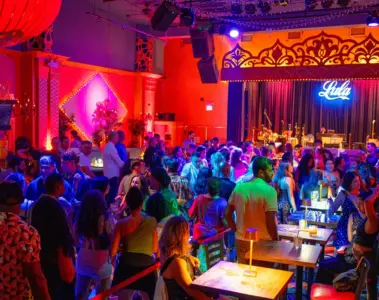 A large crowd gathers around the dance floor inside the brightly lit Lula Lounge.