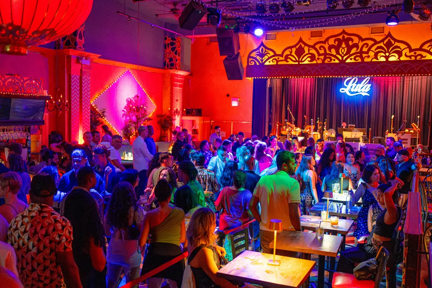 A large crowd gathers around the dance floor inside the brightly lit Lula Lounge.