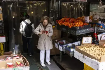 A shopper choosing fruit and vegetables at a Toronto Chinatown market