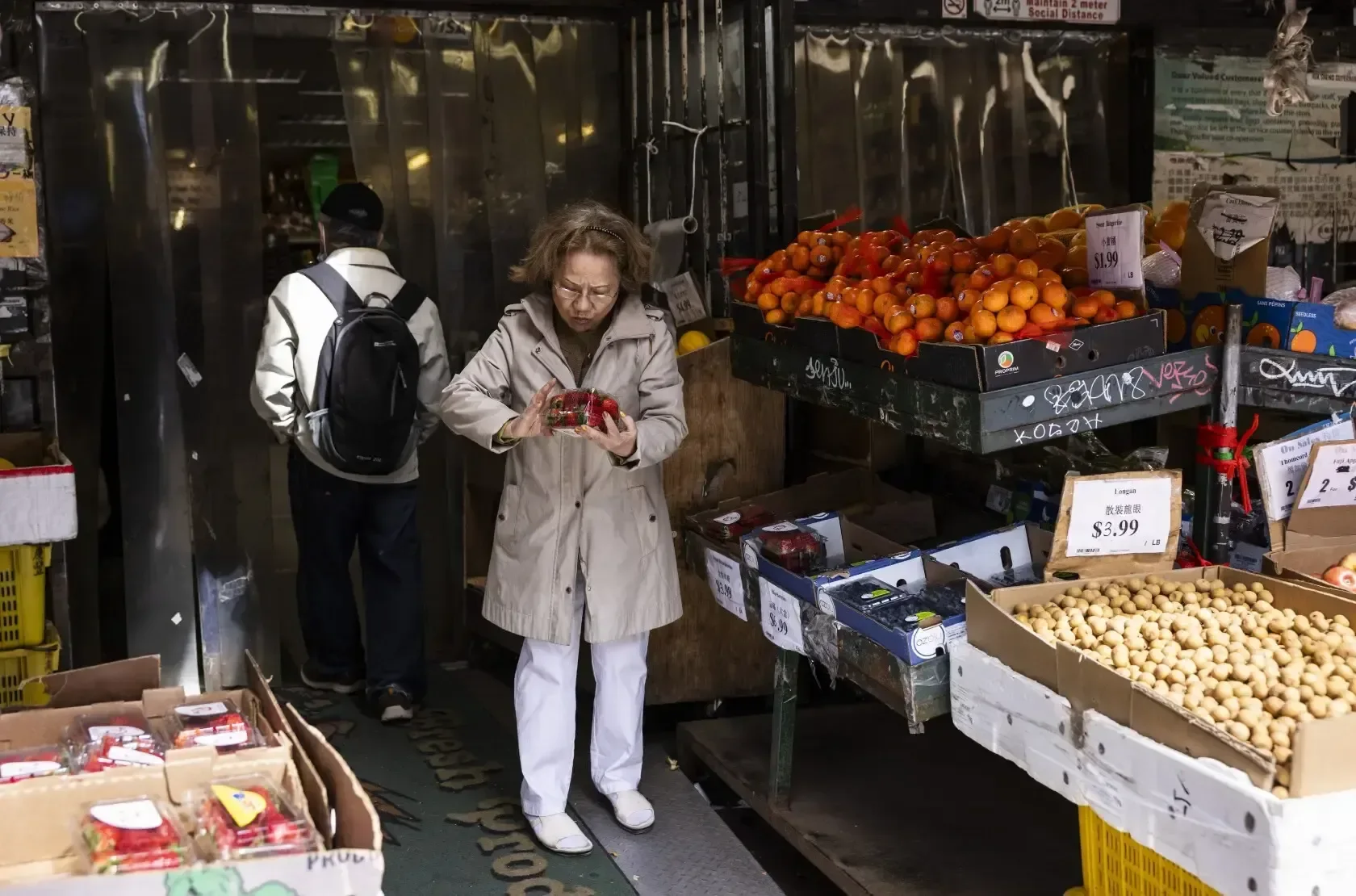 A shopper choosing fruit and vegetables at a Toronto Chinatown market