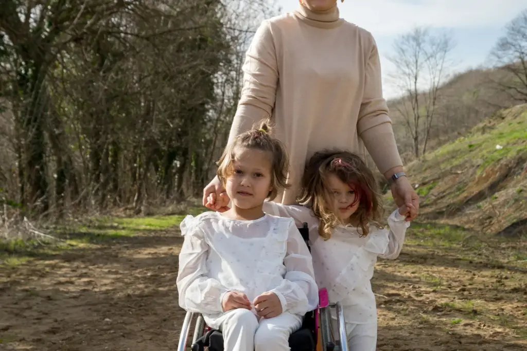 Mother with two daughters, including one child using a wheelchair, outdoors together