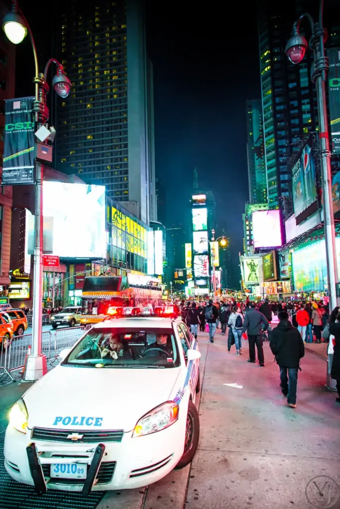 Crowds, bright signs and a police car in Times Square at night