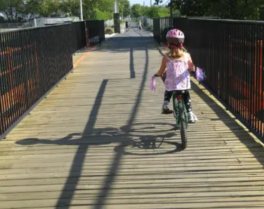 A child cycling on the West Toronto Railpath bridge