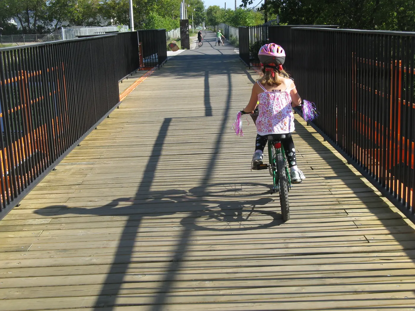 A child cycling on the West Toronto Railpath bridge