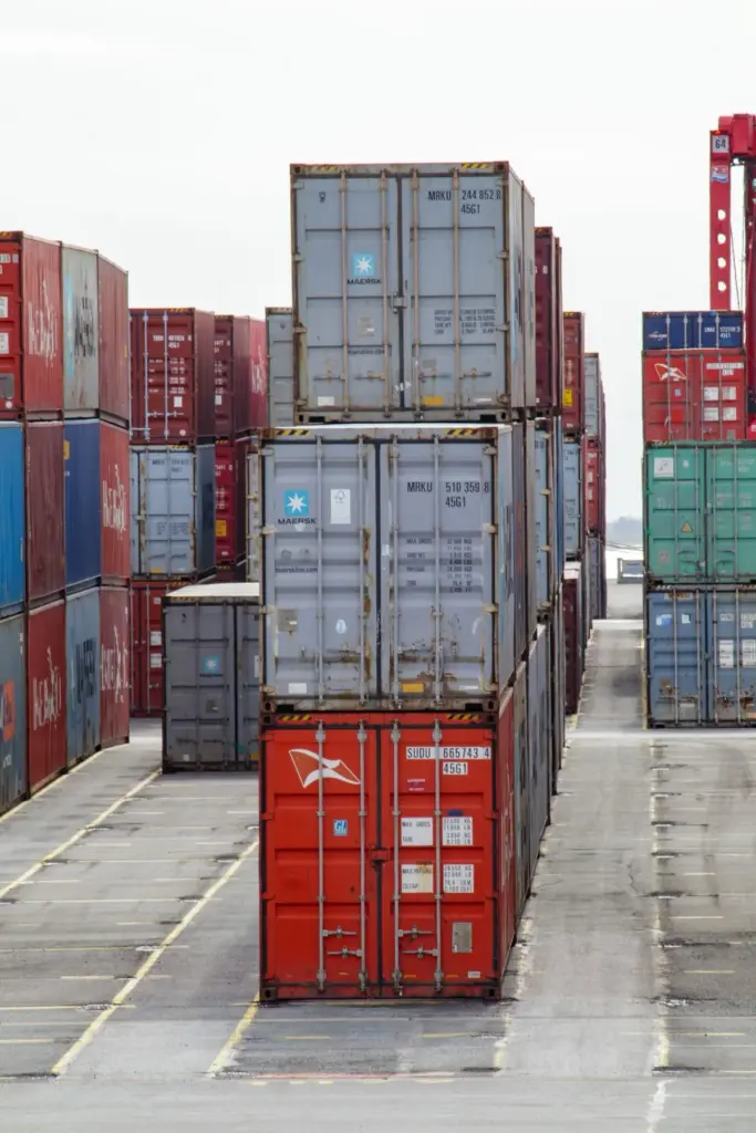 Tall stacks of shipping containers on a wet port lot