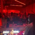 A DJ faces a crowded dance floor under red lights at Standard Time on Geary Avenue.