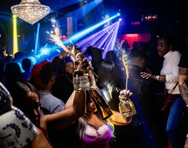 A diverse group celebrates with bottle service inside SU Karaoke