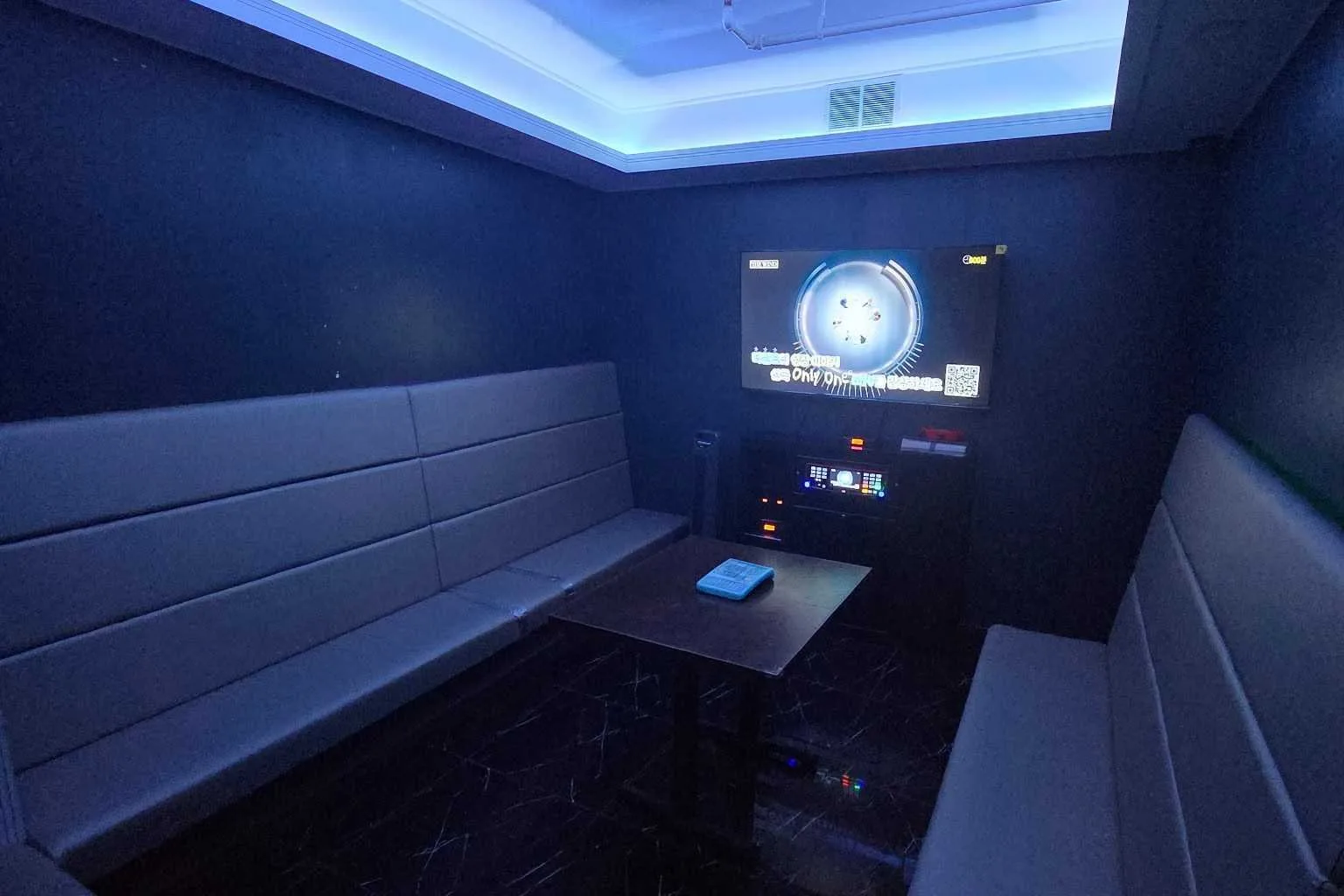 A private karaoke room with wraparound seating and blue lighting at SU Karaoke