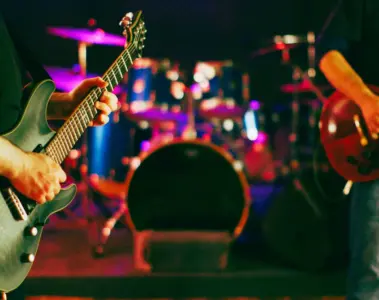 Two musicians play guitars inside a rehearsal studio at The Best Deal in Town