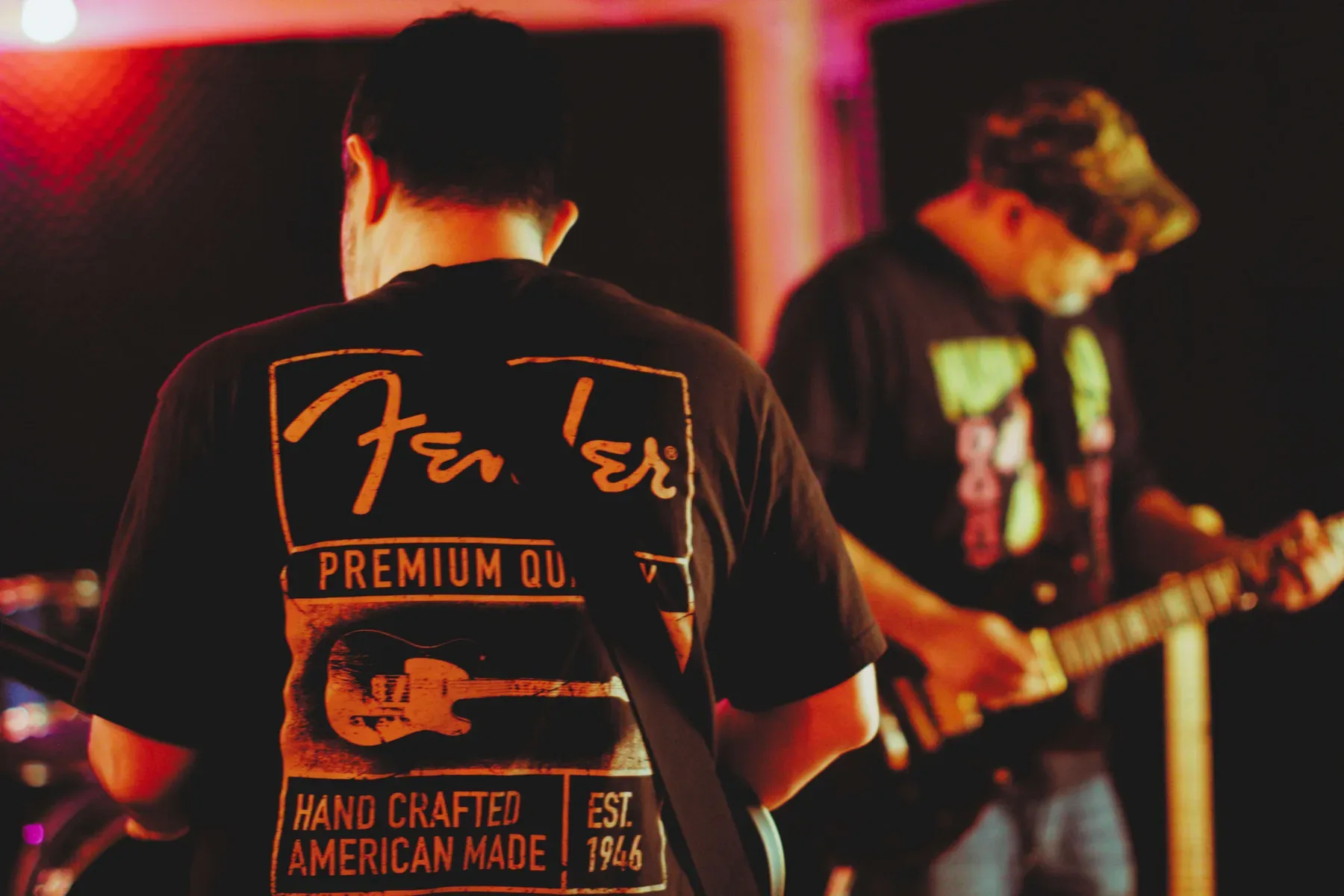 Musicians rehearse inside a warm red-lit studio at The Best Deal in Town