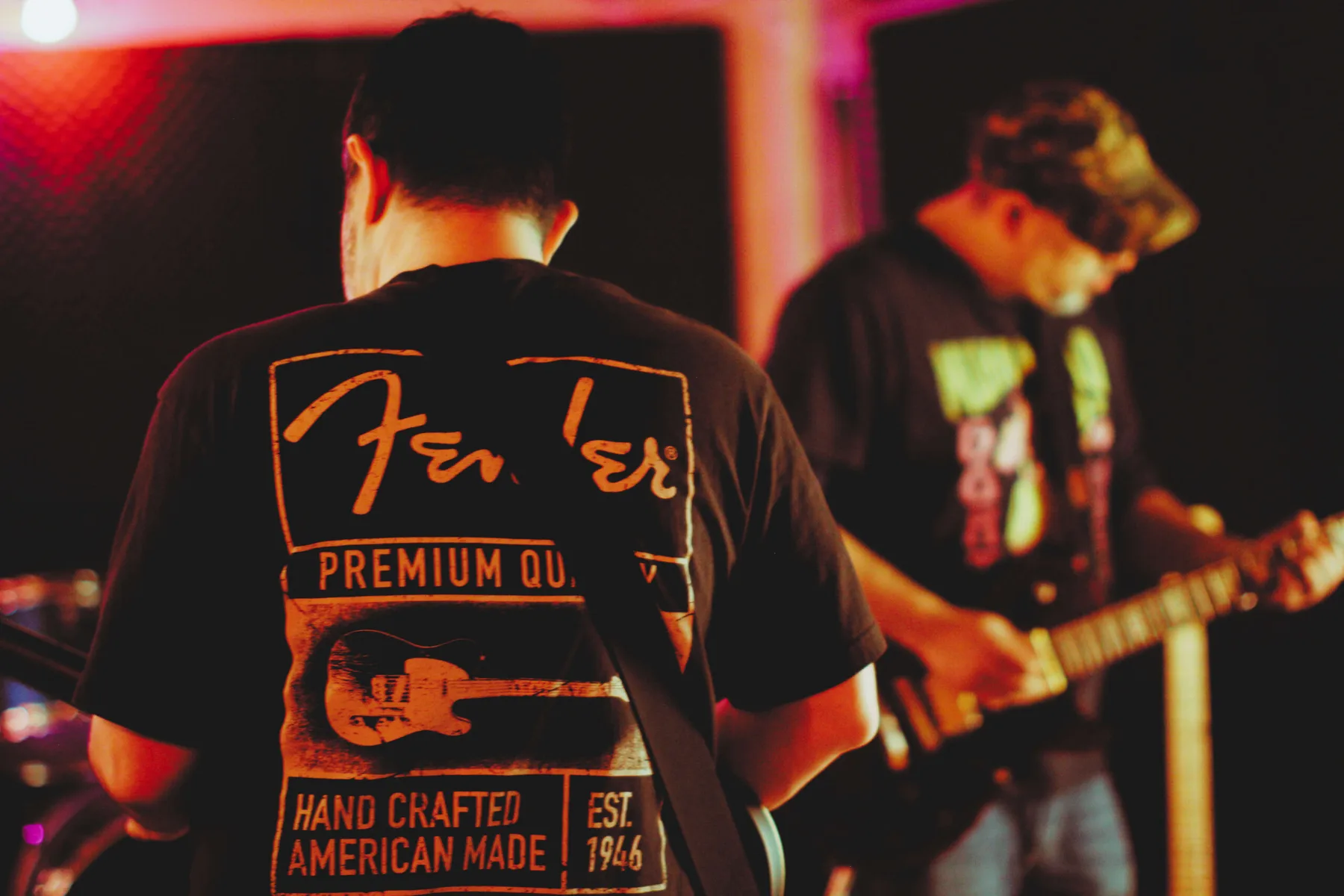 Musicians rehearse inside a warm red-lit studio at The Best Deal in Town