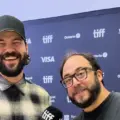 Rodrigo Fernandez-Stoll and Logan Graham Greene smiling in front of a TIFF media wall
