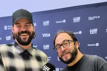 Rodrigo Fernandez-Stoll and Logan Graham Greene smiling in front of a TIFF media wall