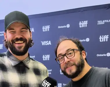 Rodrigo Fernandez-Stoll and Logan Graham Greene smiling in front of a TIFF media wall