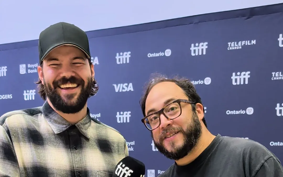 Rodrigo Fernandez-Stoll and Logan Graham Greene smiling in front of a TIFF media wall