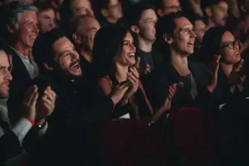 A diverse audience smiles and applauds inside a TIFF cinema