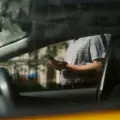 Person checking a smartphone beside a car