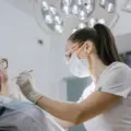 Female dentist wearing a mask while examining an older patient in a bright clinic