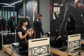 Women and instructors using reformer machines in a Pilates studio