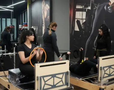 Women and instructors using reformer machines in a Pilates studio