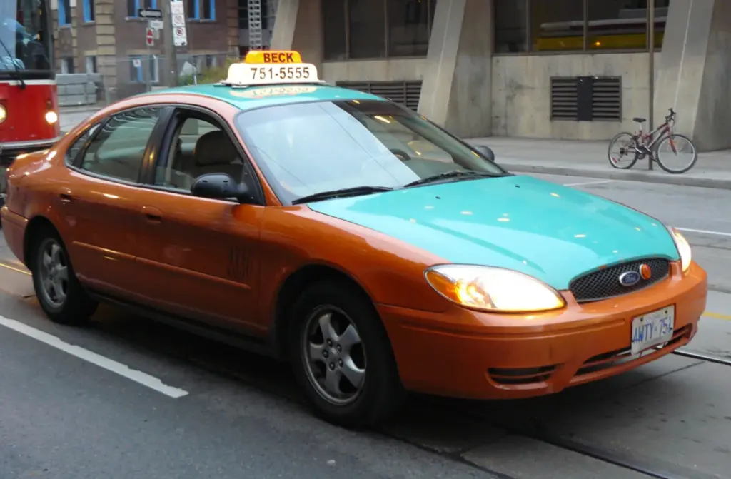 Orange and green licensed Toronto taxi on a downtown street