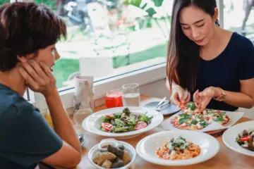 Three women sharing pizza and drinks at a casual table