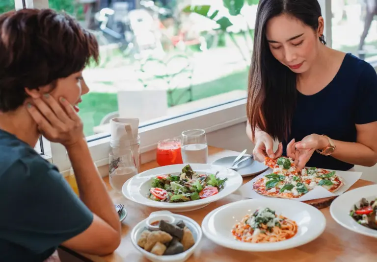 Three women sharing pizza and drinks at a casual table