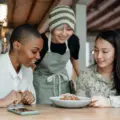 Three women sharing a meal with a restaurant worker at their table