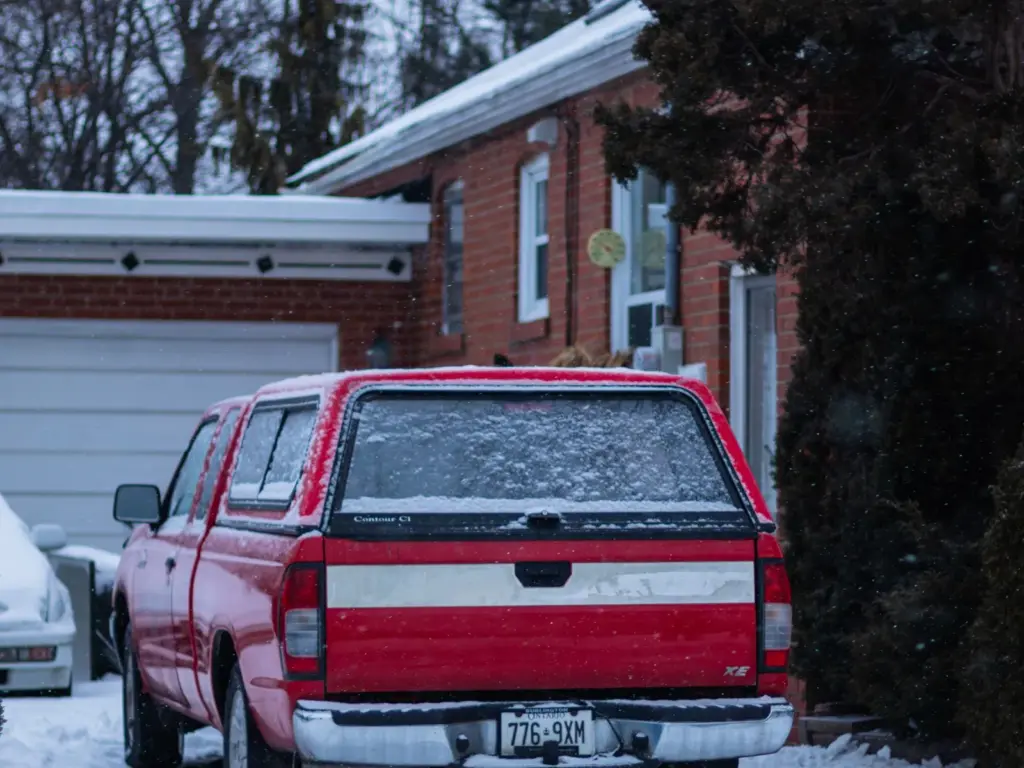 Red pickup truck parked on a snowy residential driveway in Toronto