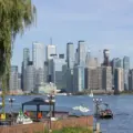 Toronto skyline across the harbour with boats, trees and outdoor seating in the foreground