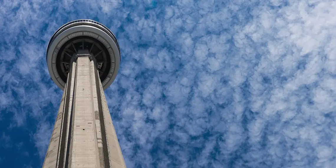 CN Tower rising above trees and downtown buildings in Toronto