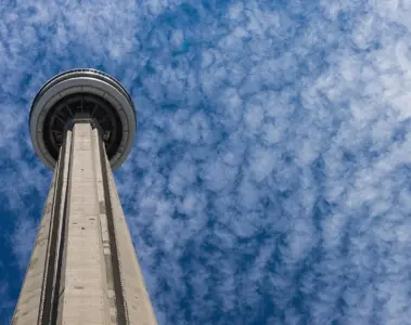 CN Tower rising above trees and downtown buildings in Toronto