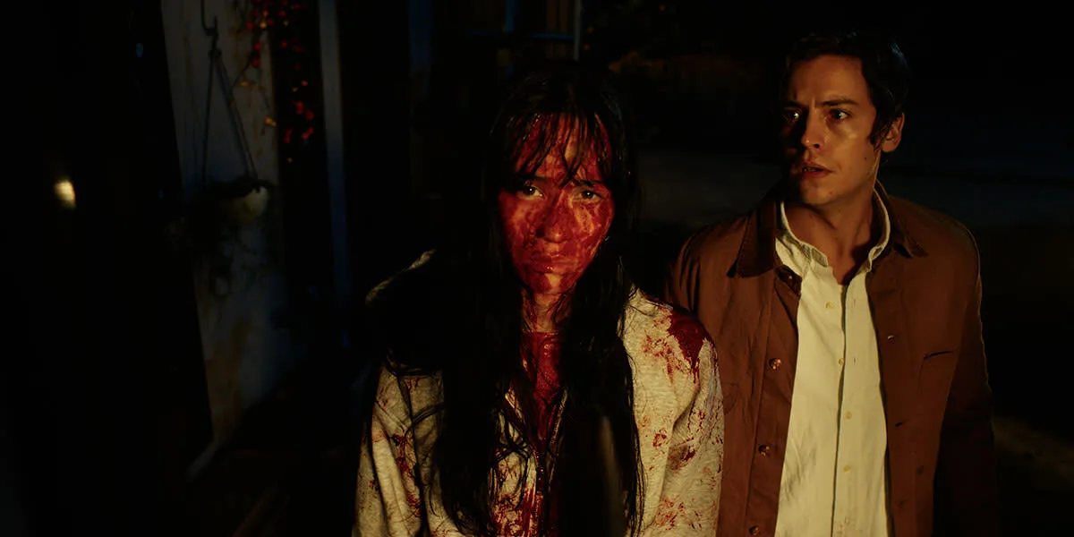 Two bloodied people stand together at night in a scene from Vintage Violence