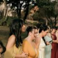 Women in colourful formal dresses standing together at an outdoor wedding
