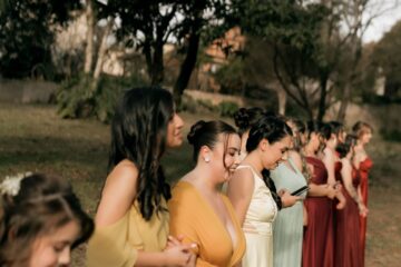 Women in colourful formal dresses standing together at an outdoor wedding
