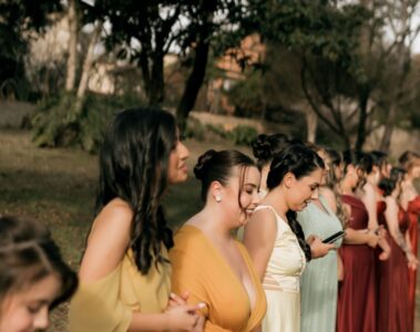 Women in colourful formal dresses standing together at an outdoor wedding