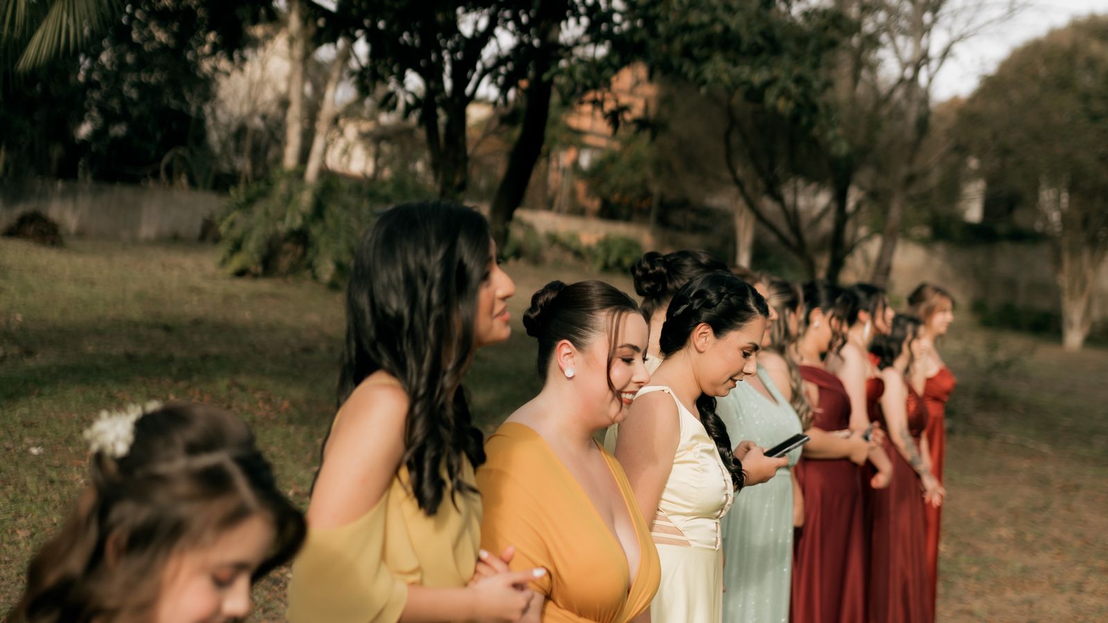 Women in colourful formal dresses standing together at an outdoor wedding