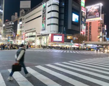 Bright shops and pedestrians around Shibuya Crossing in Tokyo at night