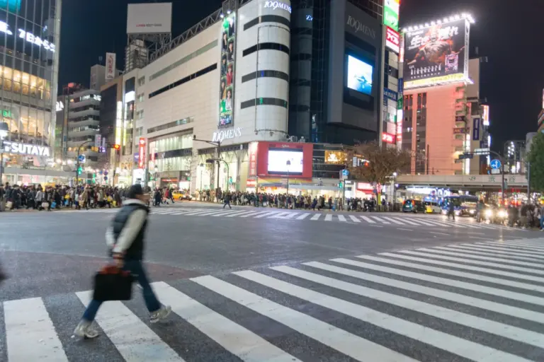 Bright shops and pedestrians around Shibuya Crossing in Tokyo at night