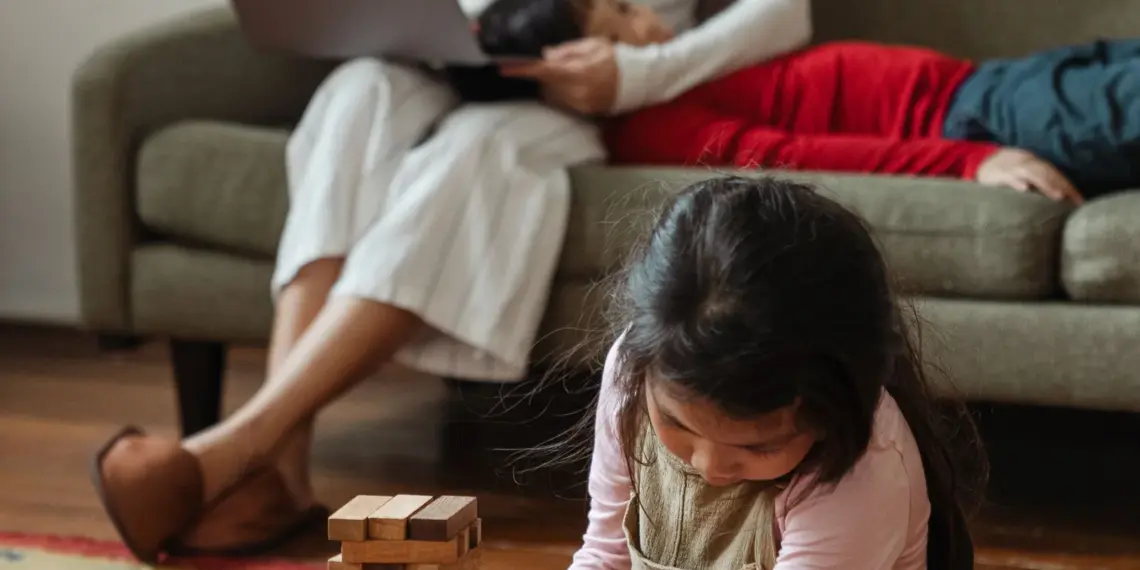 Mother working on a laptop while two young children sit beside her