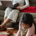 Mother working on a laptop while two young children sit beside her