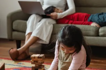 Mother working on a laptop while two young children sit beside her