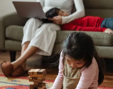 Mother working on a laptop while two young children sit beside her