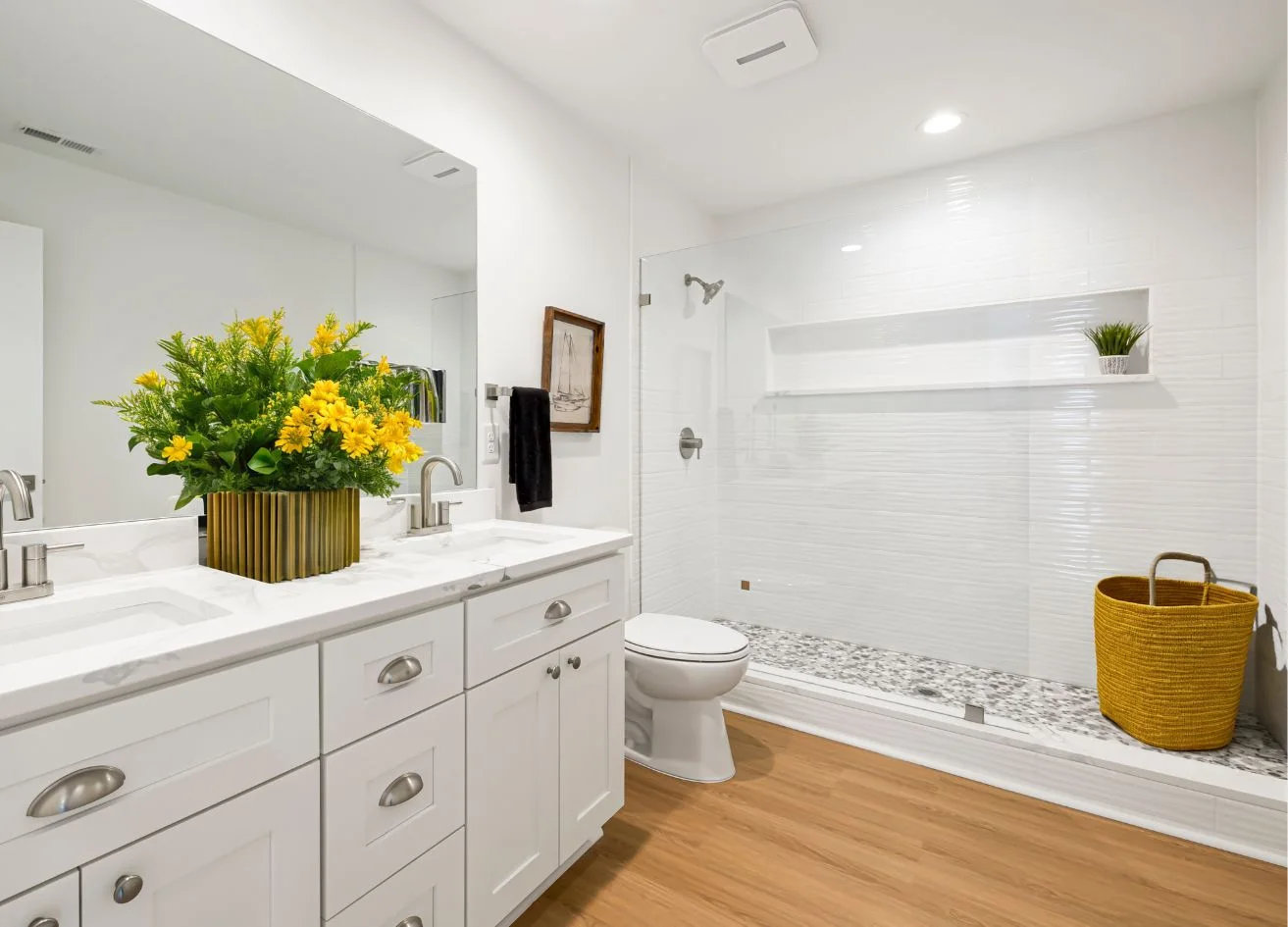 Bathroom with a tiled shower, vanity and wood floor.