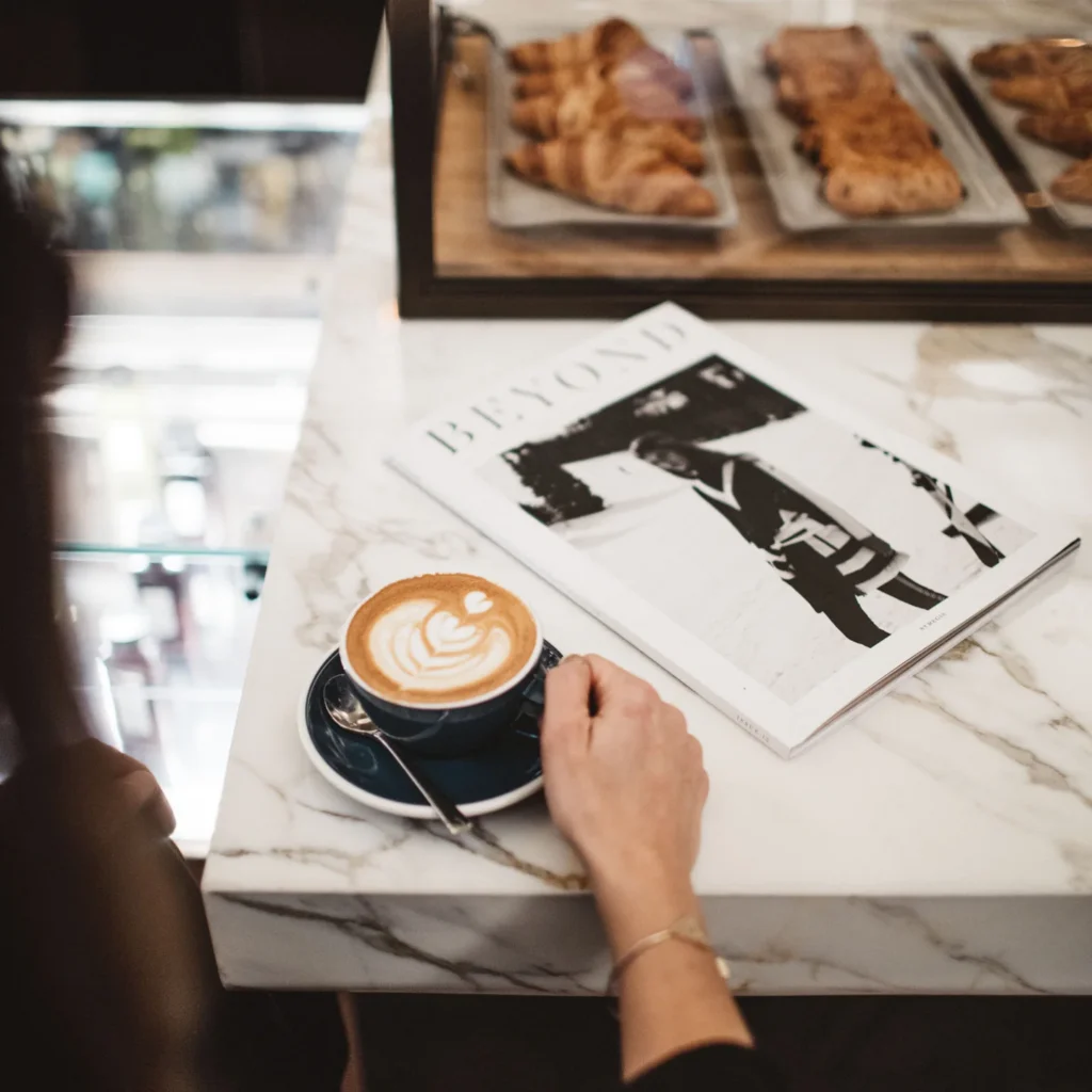 A guest holding a cup of coffee at a table in Astor Lounge