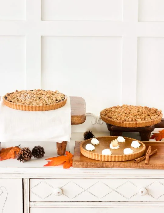 Pumpkin pie, an apple pie and a cake on a counter at Bobbette and Belle