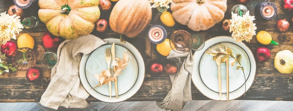 An autumn table set with plates, flowers and pumpkins