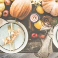An autumn table set with plates, flowers and pumpkins