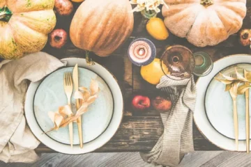 An autumn table set with plates, flowers and pumpkins