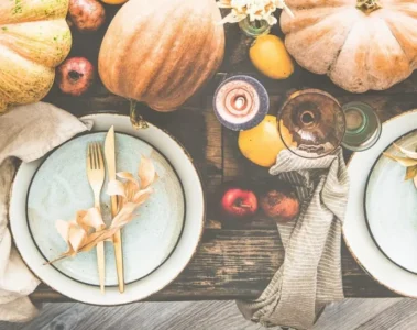 An autumn table set with plates, flowers and pumpkins
